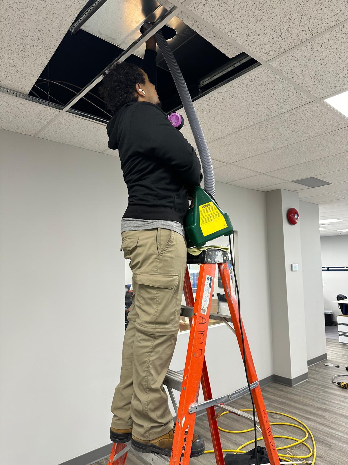 Technicien nettoyant un réseau de conduits au plafond